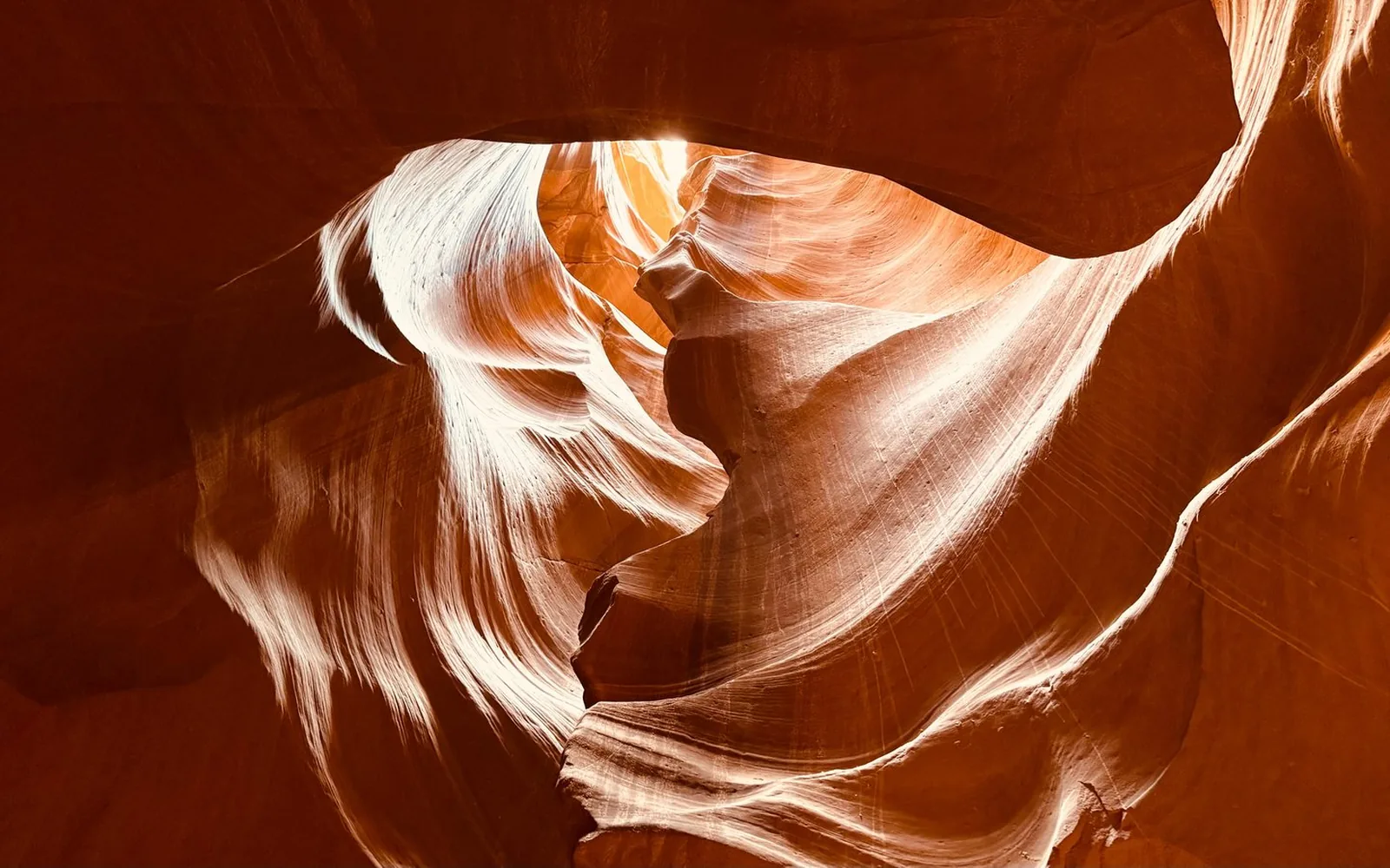 Die geschwungenen orangefarbenen Sandsteinwände des Upper Antelope Canyon, die sich zu einer hellen Öffnung über Ihnen krümmen