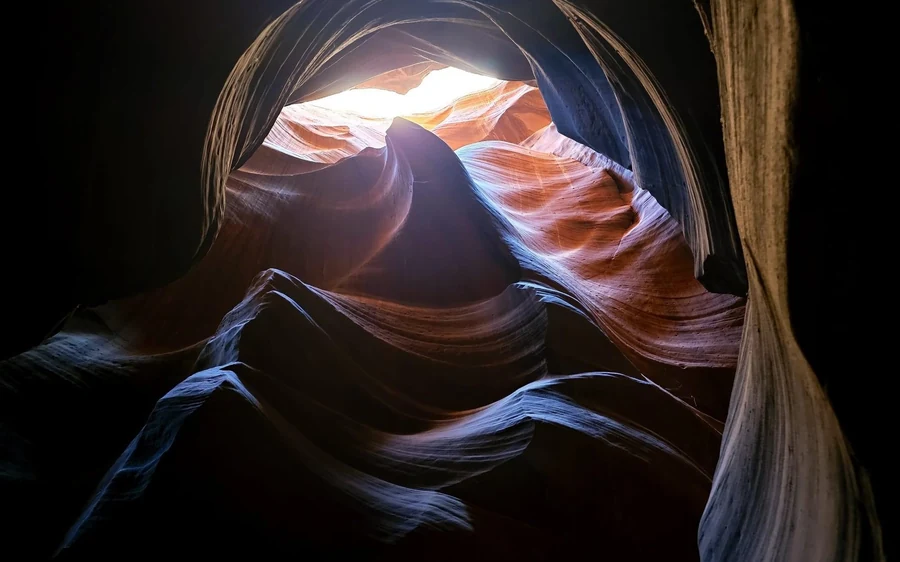 Dunkle Canyonwände in tiefem Schatten mit einer beleuchteten Öffnung weit oben