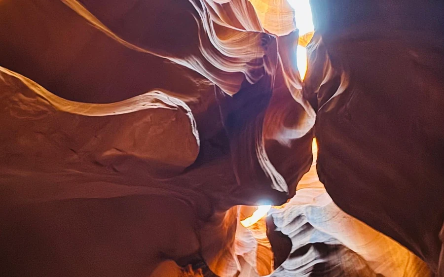 Geschwungene Canyonwände, von der Slot-Öffnung oben beleuchtet, der Boden im Schatten